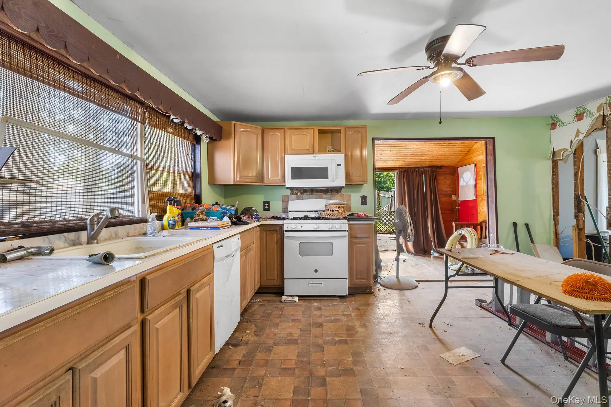 Kitchen featuring white appliances, ceiling fan, light countertops, and stone finish flooring Kitchen featuring white appliances, ceiling fan, light countertops, and stone finish flooring