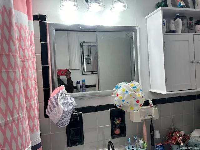 Bathroom featuring tile walls and a shower with curtain Bathroom featuring tile walls and a shower with curtain