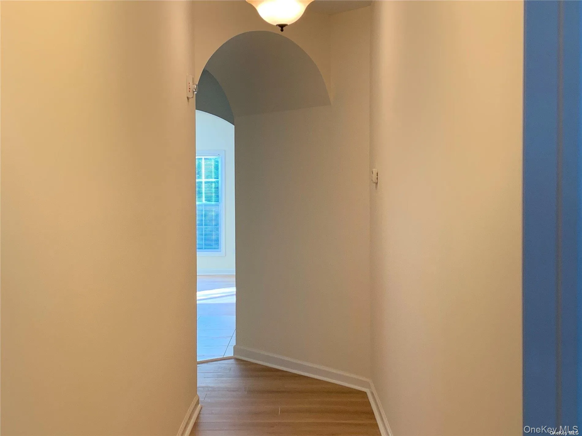 Corridor featuring arched walkways and wood finished floors Corridor featuring arched walkways and wood finished floors