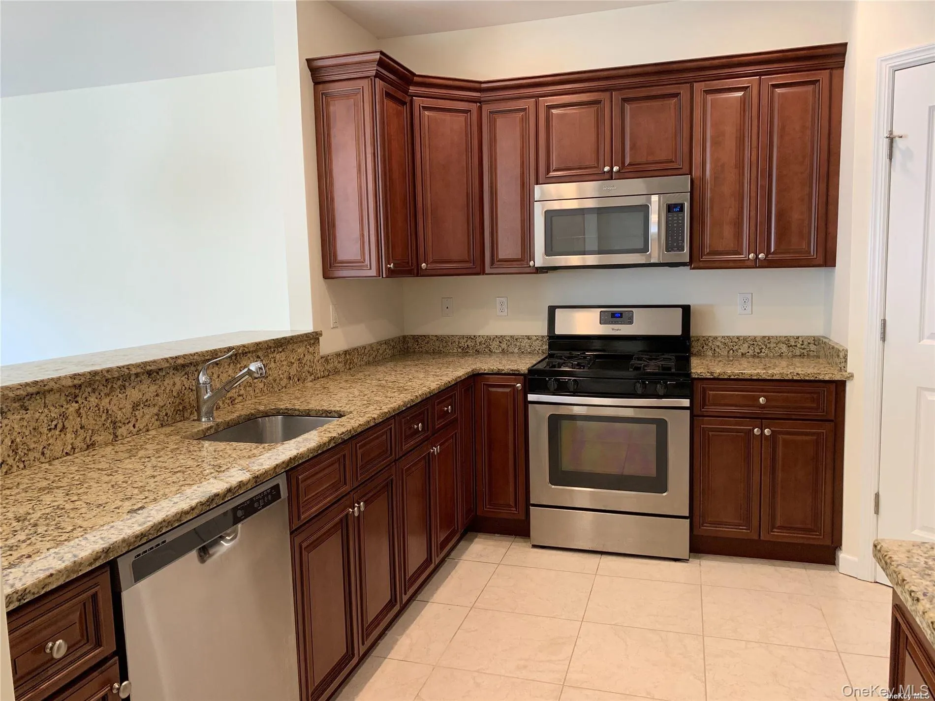 Kitchen featuring appliances with stainless steel finishes, light stone countertops, and light tile patterned floors Kitchen featuring appliances with stainless steel finishes, light stone countertops, and light tile patterned floors