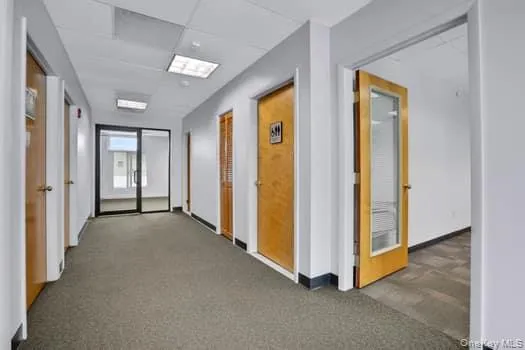 Corridor with a paneled ceiling and carpet flooring Corridor with a paneled ceiling and carpet flooring