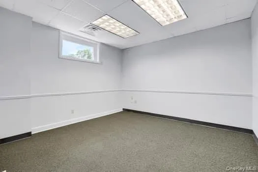 Empty room featuring a paneled ceiling and carpet flooring Empty room featuring a paneled ceiling and carpet flooring