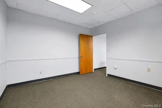 Empty room with a drop ceiling and dark colored carpet Empty room with a drop ceiling and dark colored carpet