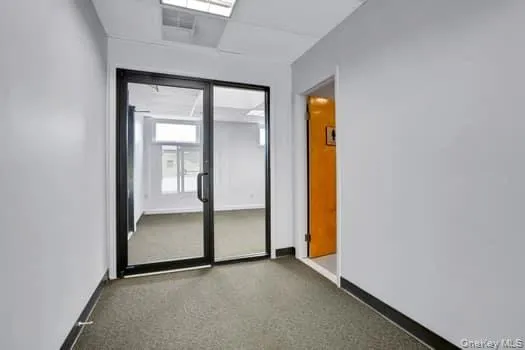 Hall featuring baseboards and dark colored carpet Hall featuring baseboards and dark colored carpet