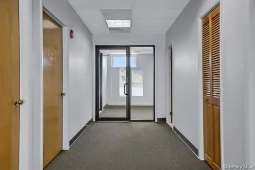 Hall featuring dark carpet Hall featuring dark carpet