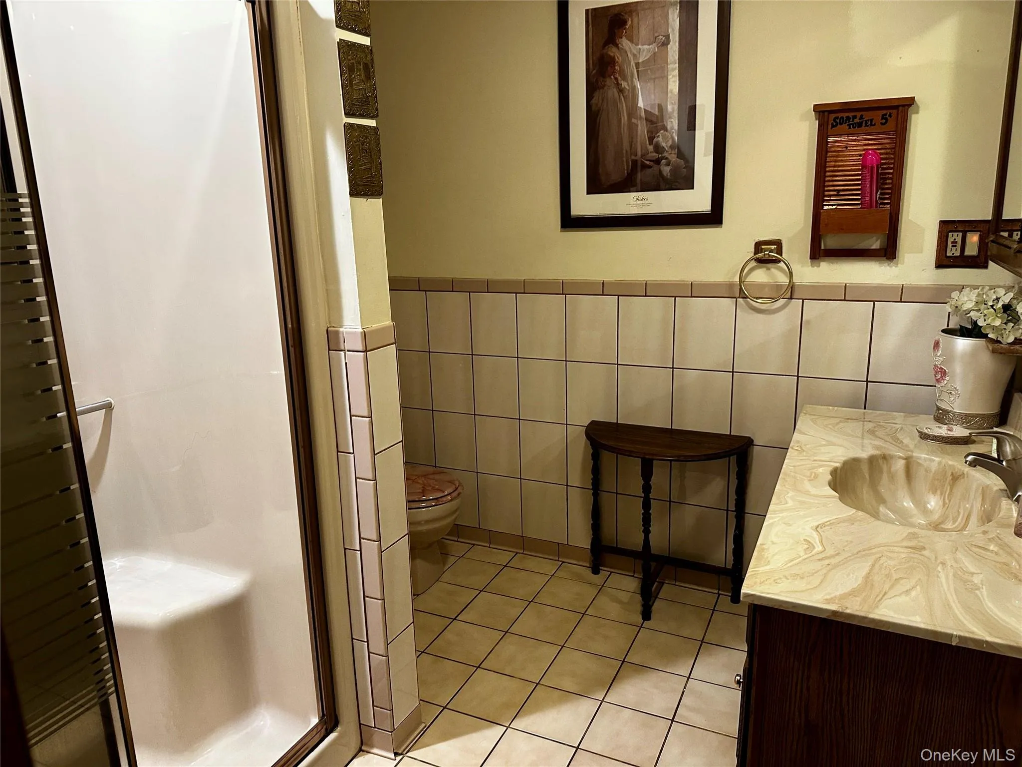 Full bath featuring a shower stall, tile walls, vanity, tile patterned floors, and a wainscoted wall Full bath featuring a shower stall, tile walls, vanity, tile patterned floors, and a wainscoted wall