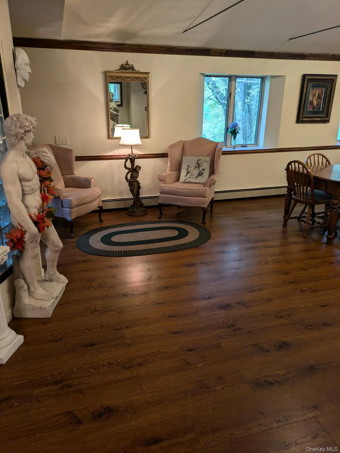 Sitting room with dark wood finished floors, crown molding, and a baseboard heating unit Sitting room with dark wood finished floors, crown molding, and a baseboard heating unit