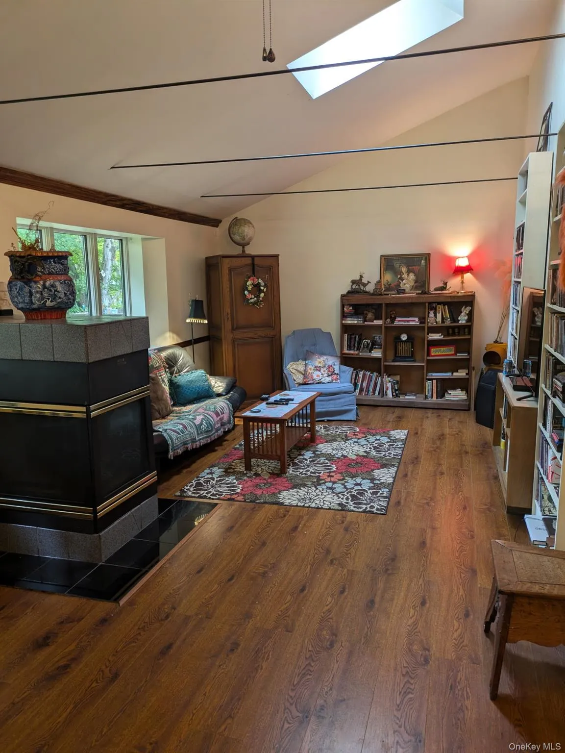 Living room with a skylight, vaulted ceiling, and dark wood-style floors Living room with a skylight, vaulted ceiling, and dark wood-style floors
