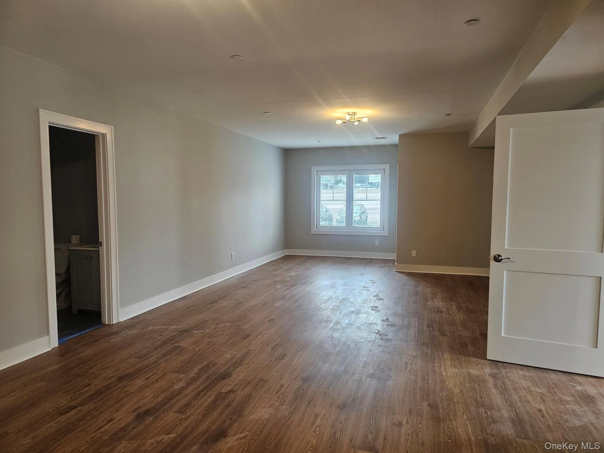 Spare room with baseboards and dark wood-style flooring Spare room with baseboards and dark wood-style flooring