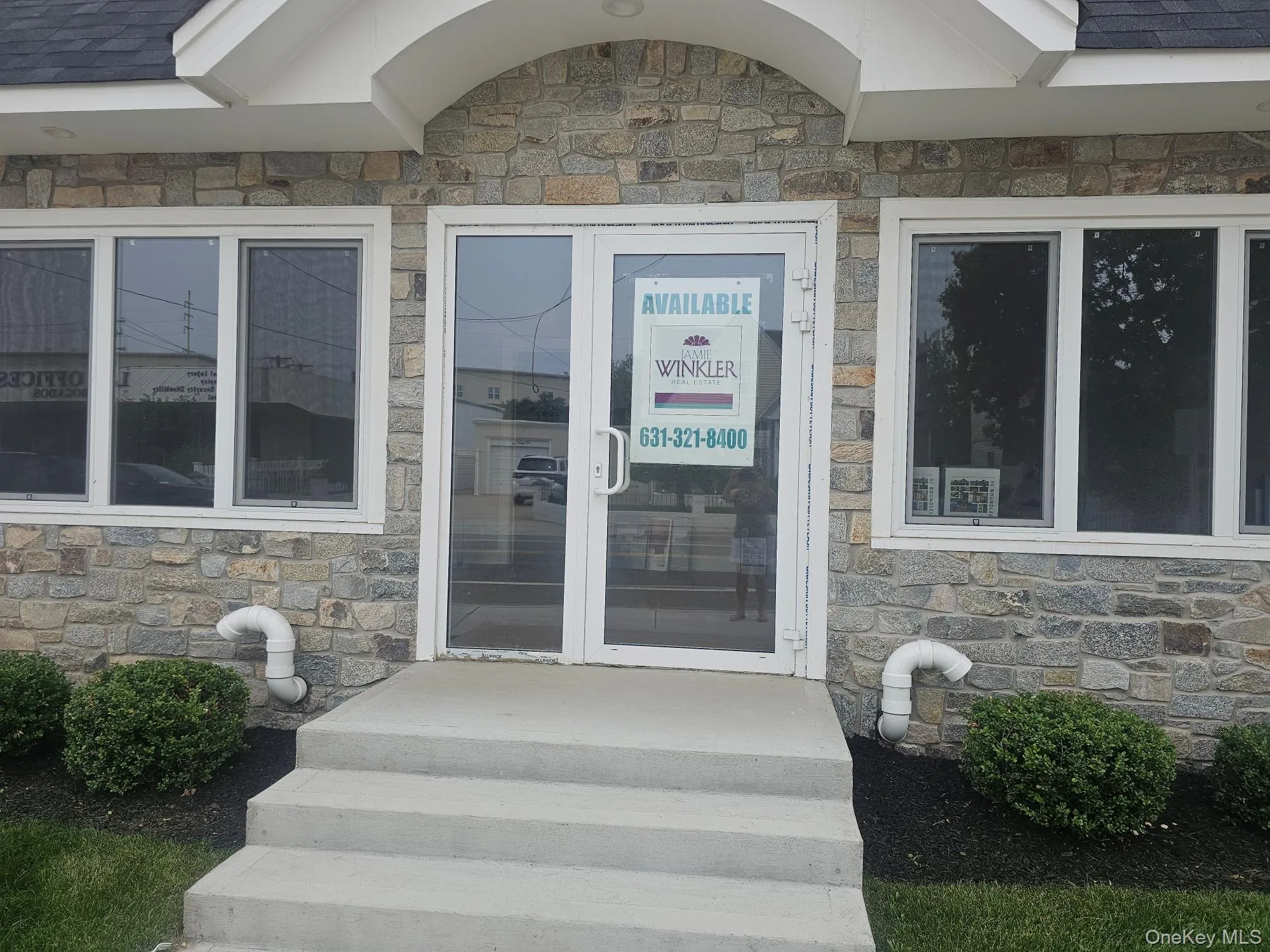 View of exterior entry featuring stone siding and a shingled roof View of exterior entry featuring stone siding and a shingled roof