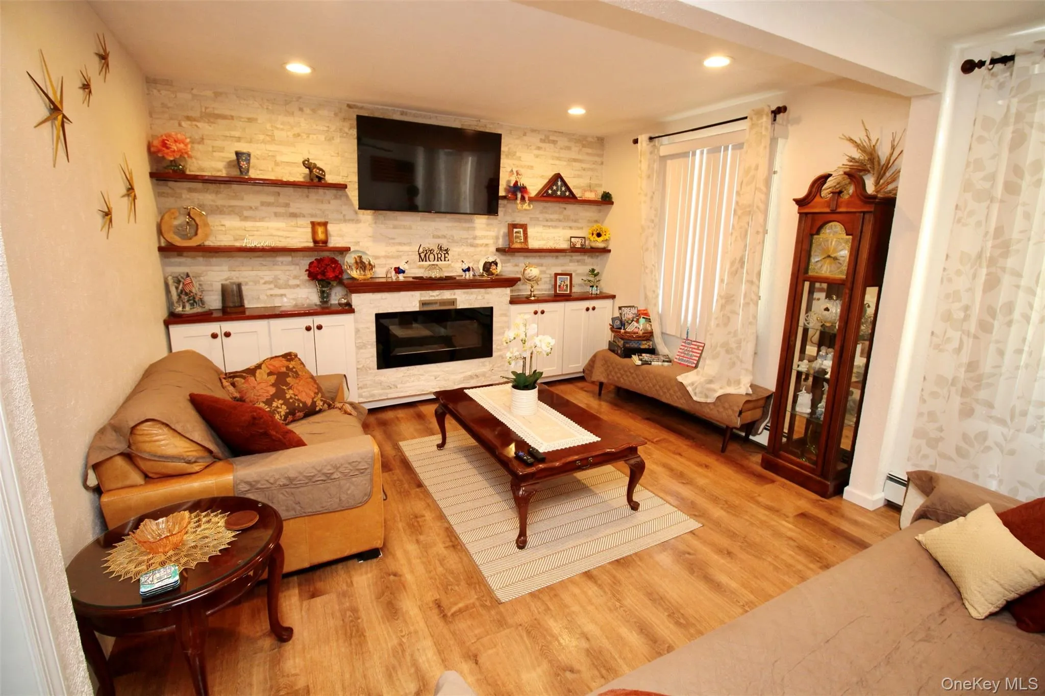 Living room featuring light wood-style floors, a large fireplace, and recessed lighting Living room featuring light wood-style floors, a large fireplace, and recessed lighting