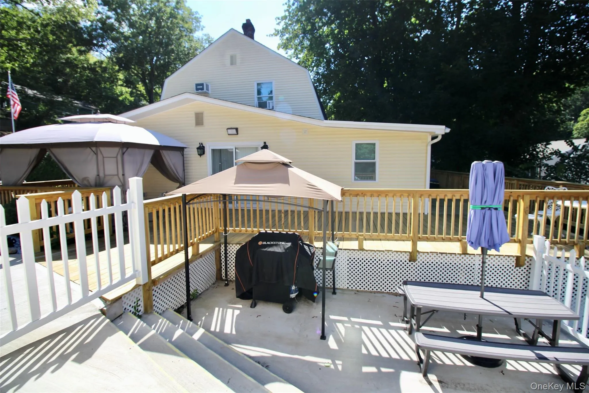 Wooden deck with a gazebo, a patio, area for grilling, and outdoor dining space Wooden deck with a gazebo, a patio, area for grilling, and outdoor dining space