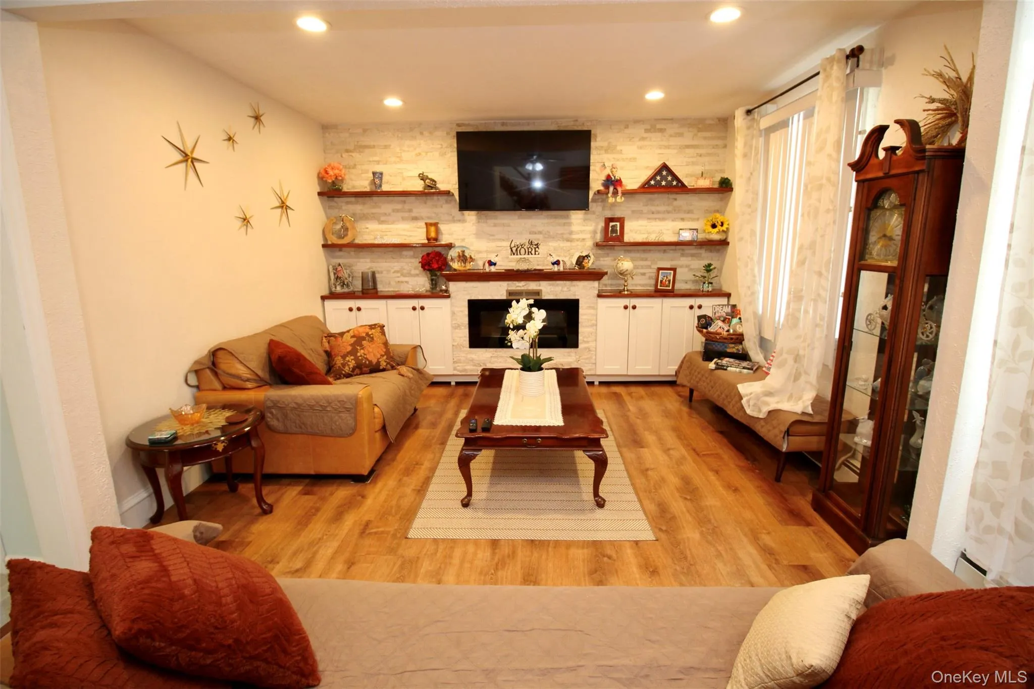 Living area with a large fireplace, light wood-style floors, recessed lighting, and baseboard heating Living area with a large fireplace, light wood-style floors, recessed lighting, and baseboard heating