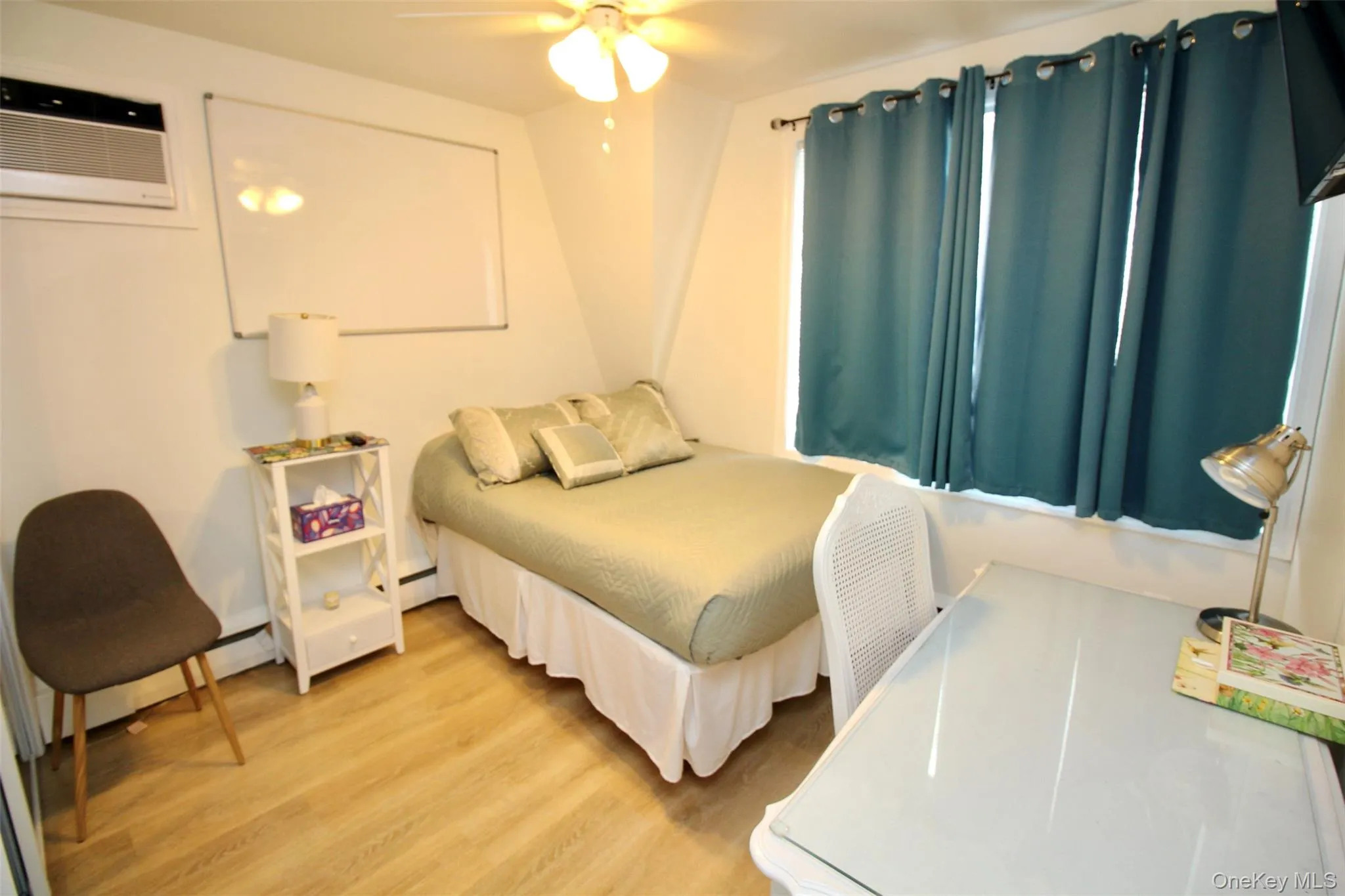 Bedroom featuring light wood-style flooring, a ceiling fan, and a wall unit AC Bedroom featuring light wood-style flooring, a ceiling fan, and a wall unit AC