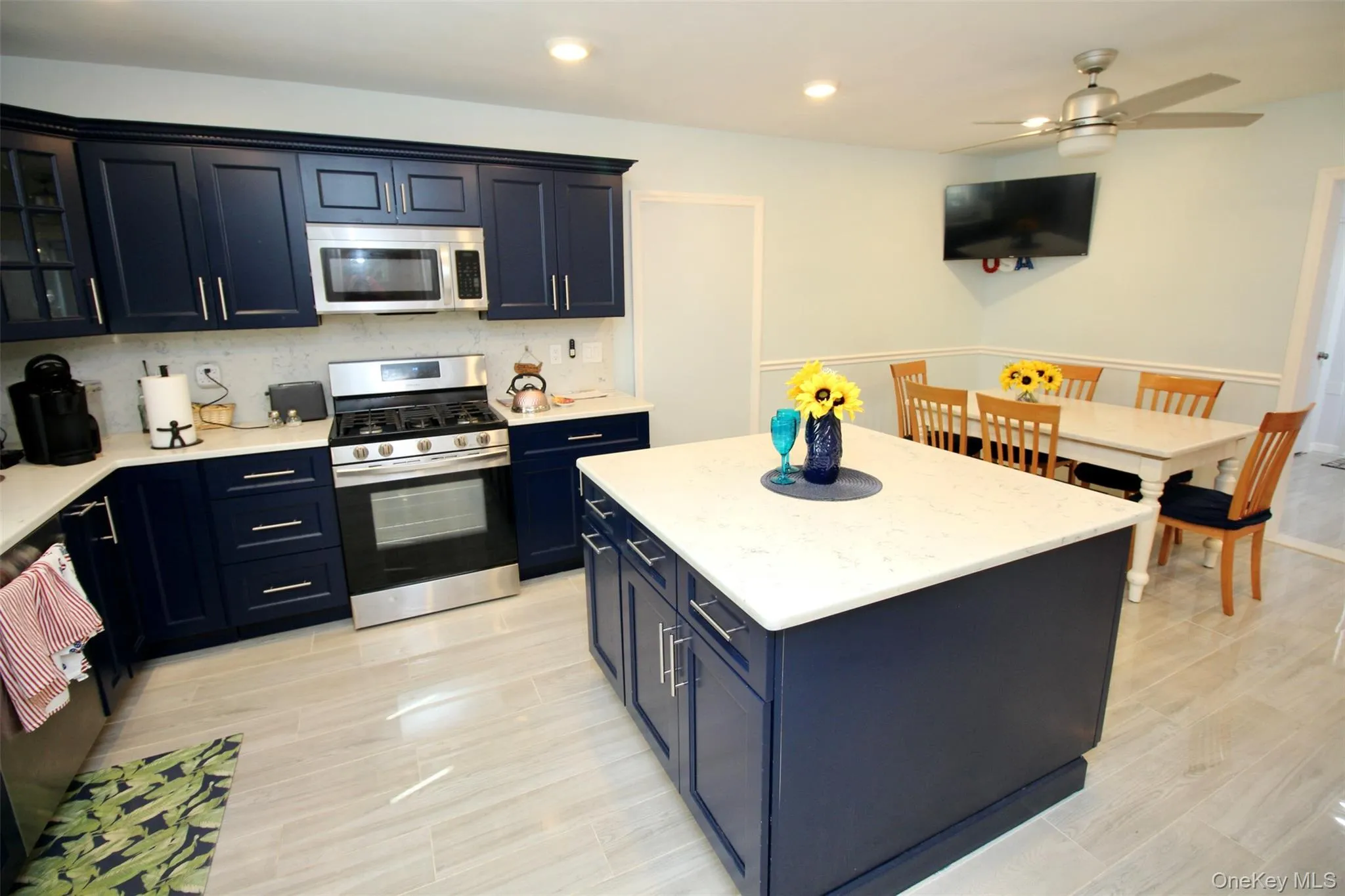 Kitchen featuring stainless steel appliances, a kitchen island, blue cabinets, recessed lighting, and light stone counters Kitchen featuring stainless steel appliances, a kitchen island, blue cabinets, recessed lighting, and light stone counters