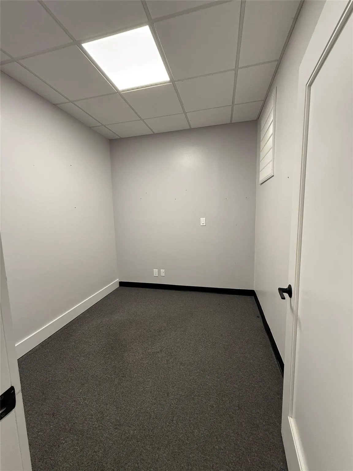 Spare room with a paneled ceiling and dark carpet Spare room with a paneled ceiling and dark carpet