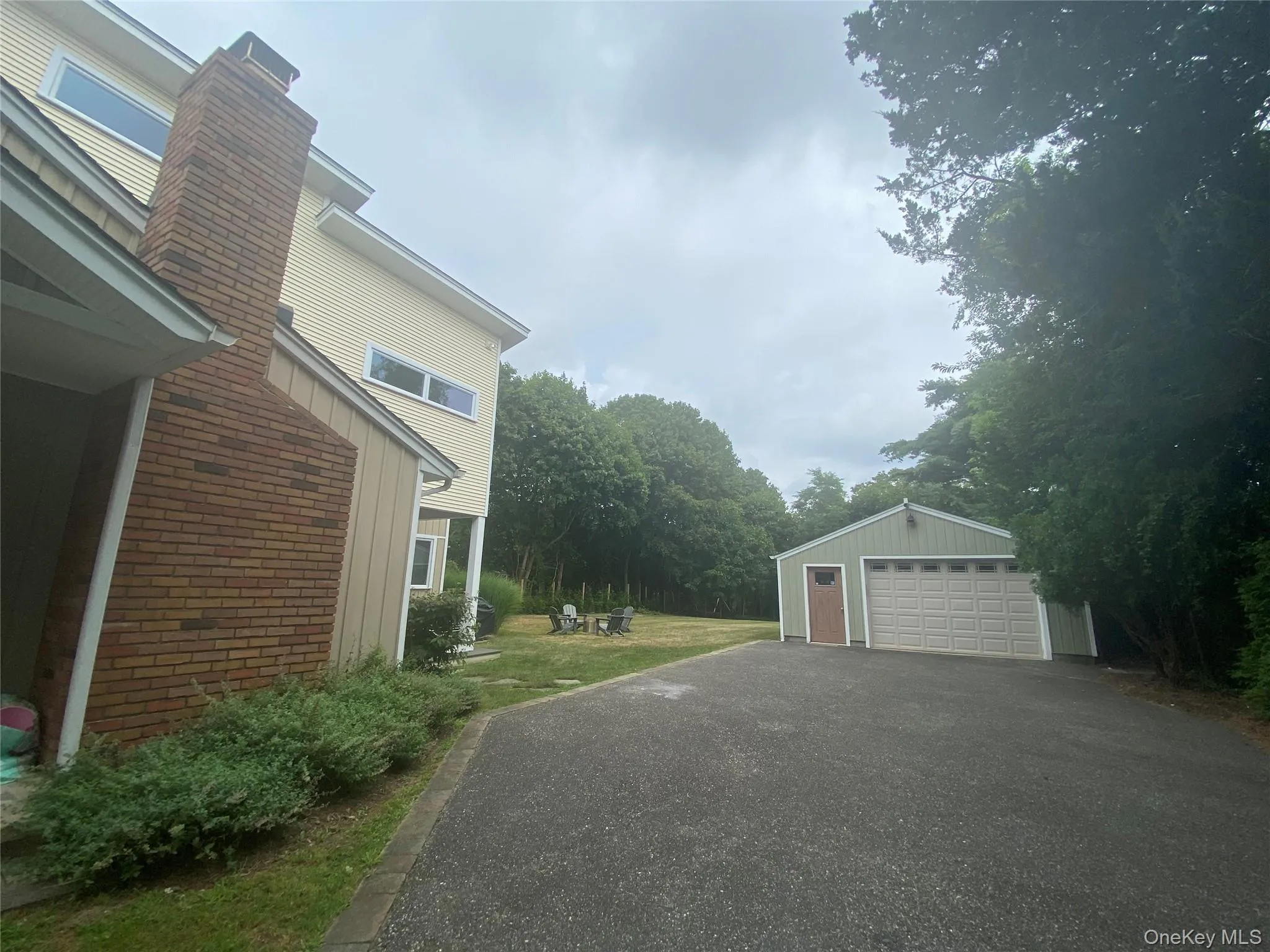 View of home's exterior featuring brick siding, an outbuilding, a chimney, a detached garage, and board and batten siding View of home's exterior featuring brick siding, an outbuilding, a chimney, a detached garage, and board and batten siding