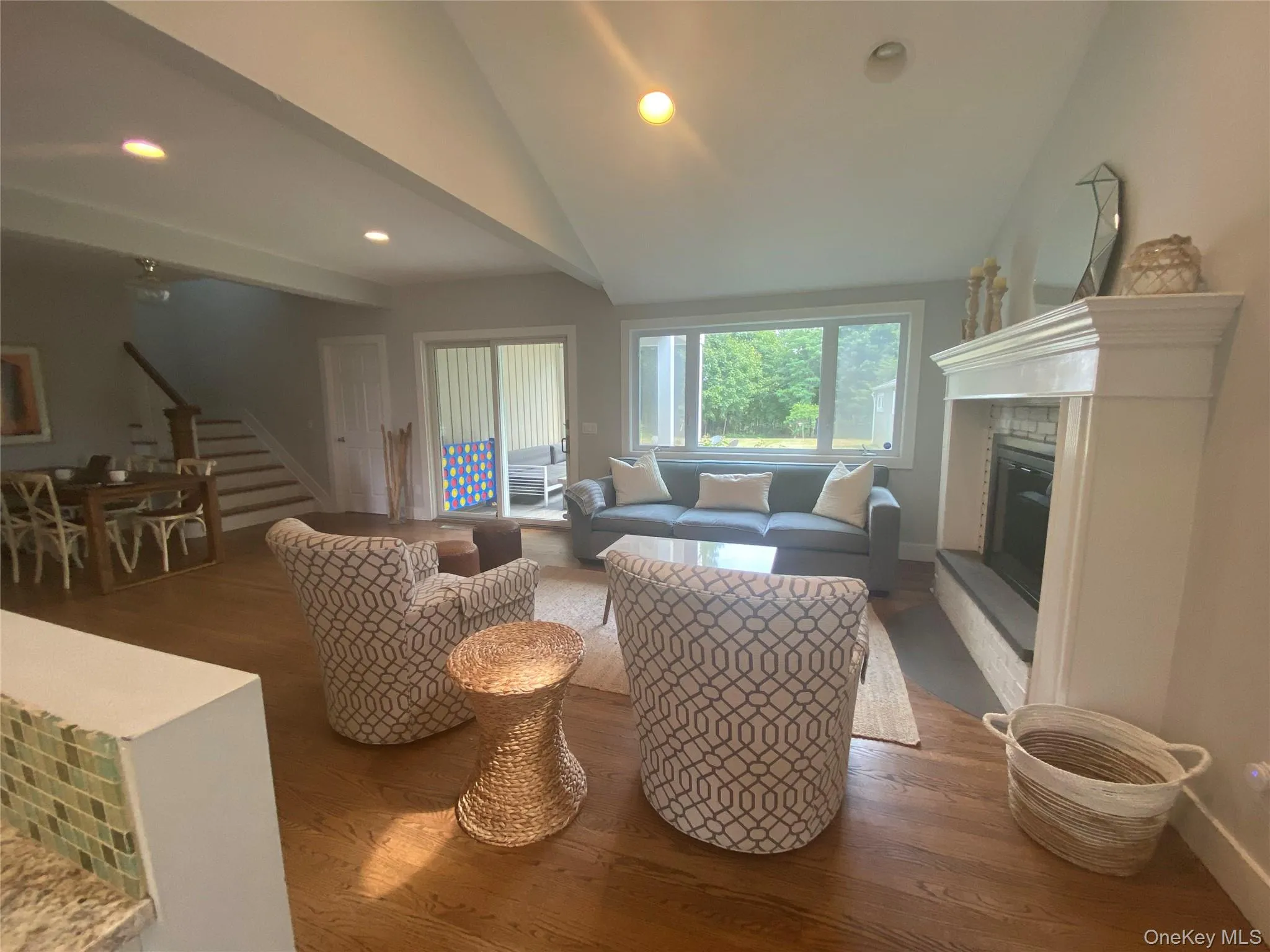 Living area with recessed lighting, stairway, lofted ceiling, a glass covered fireplace, and wood finished floors Living area with recessed lighting, stairway, lofted ceiling, a glass covered fireplace, and wood finished floors