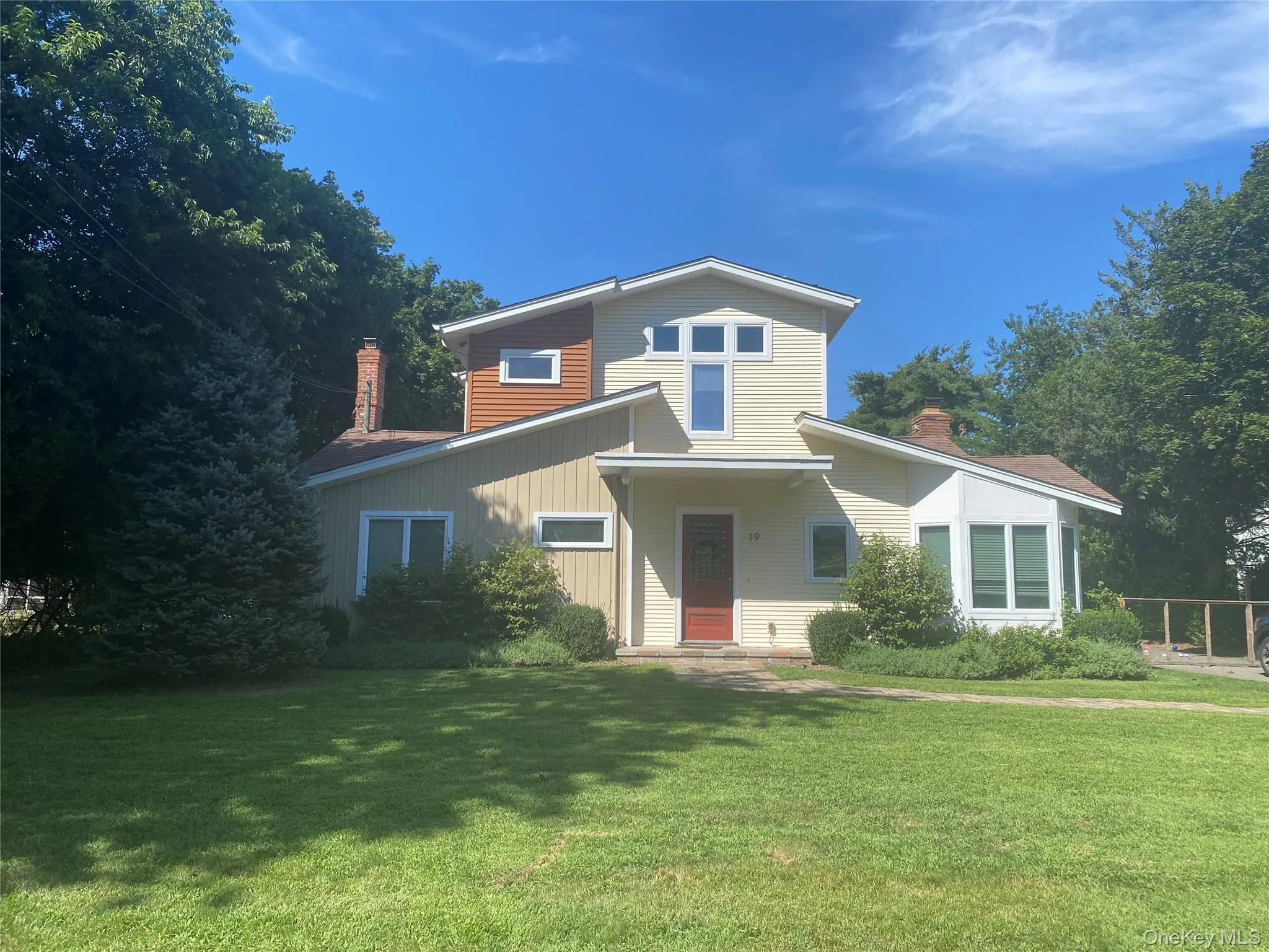 Contemporary house featuring a chimney, a front lawn, and board and batten siding Contemporary house featuring a chimney, a front lawn, and board and batten siding