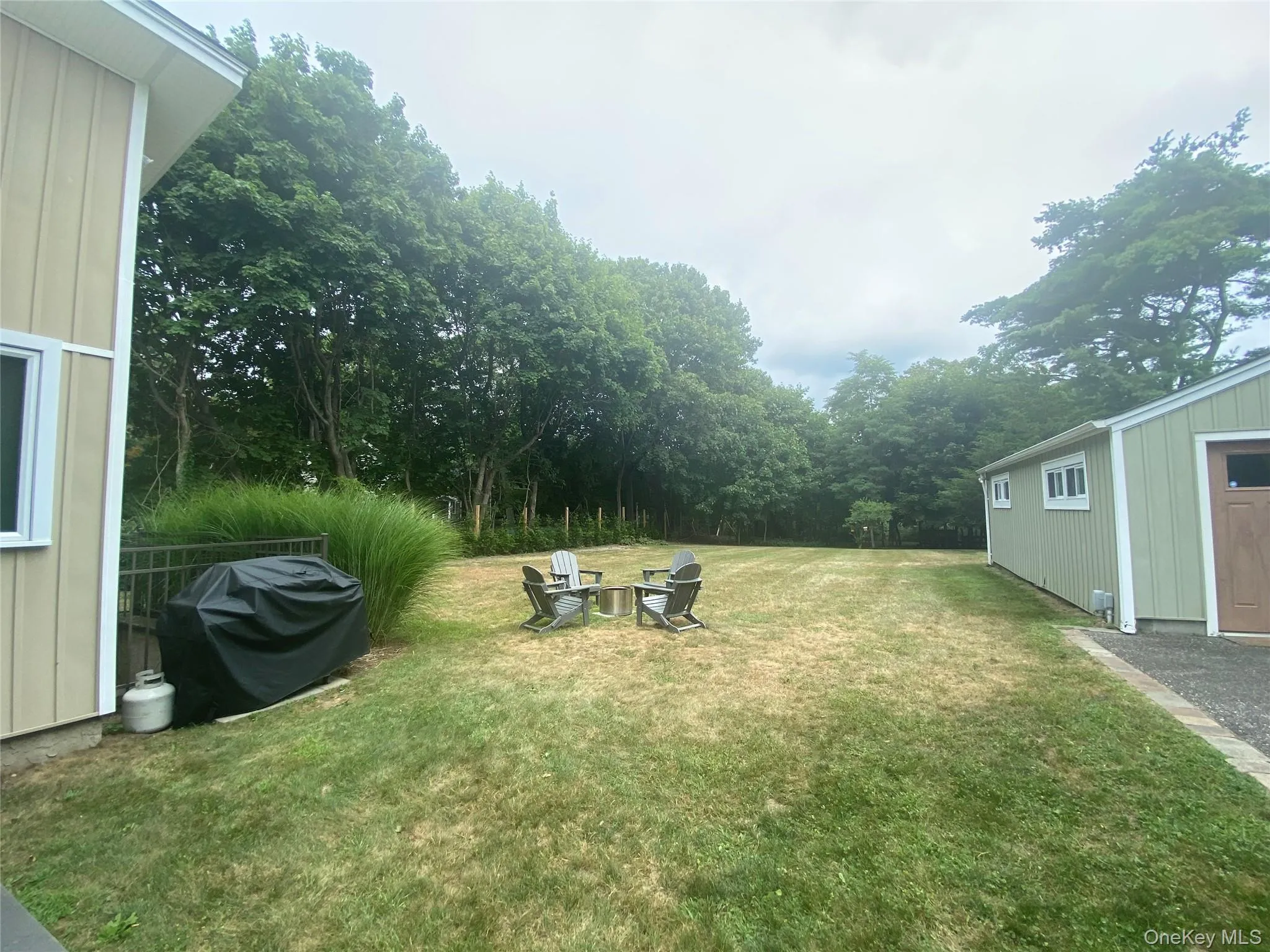 View of grassy yard with an outdoor fire pit and an outbuilding View of grassy yard with an outdoor fire pit and an outbuilding