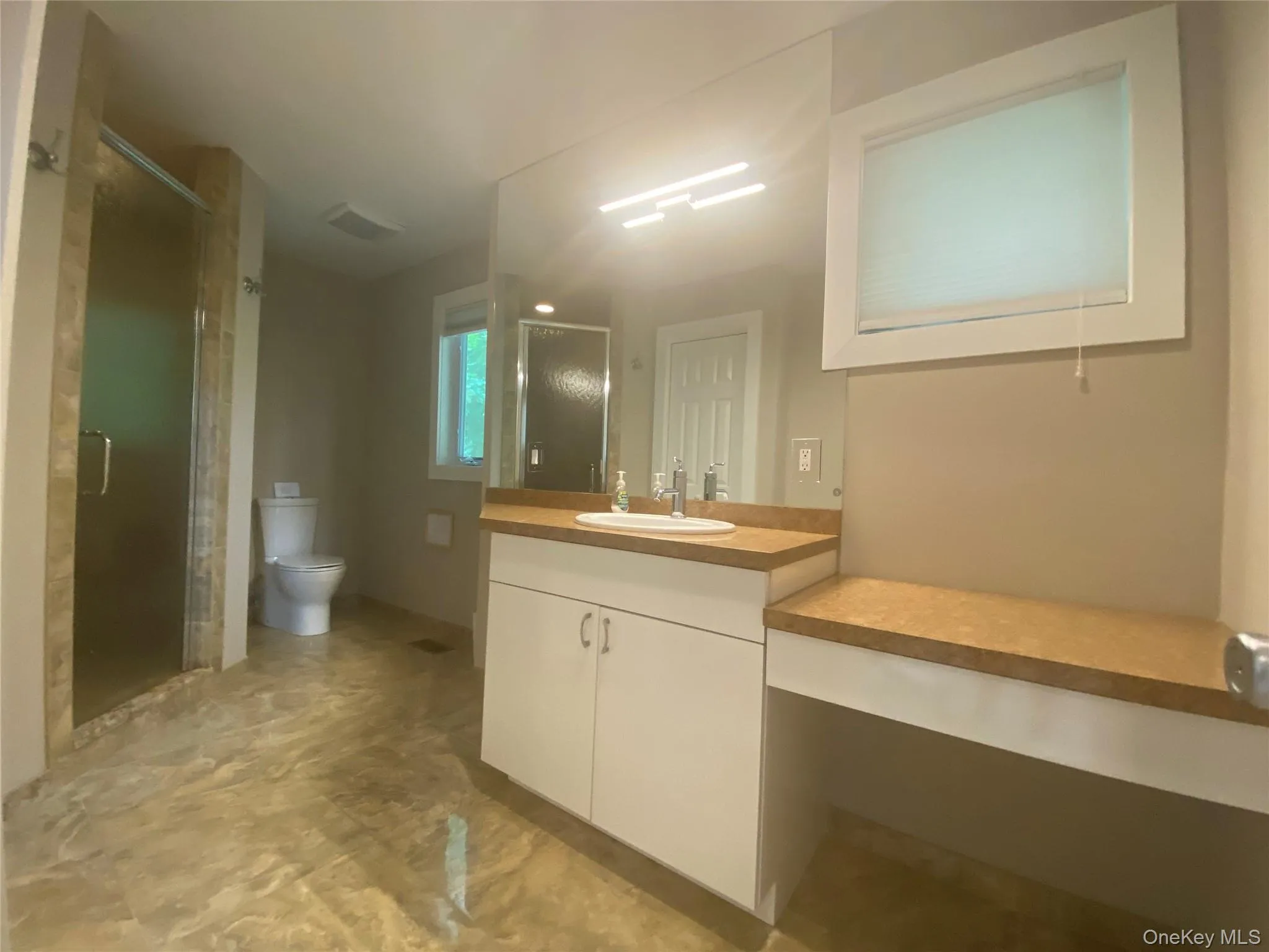 Full bath featuring vanity, a shower stall, and marble finish flooring Full bath featuring vanity, a shower stall, and marble finish flooring