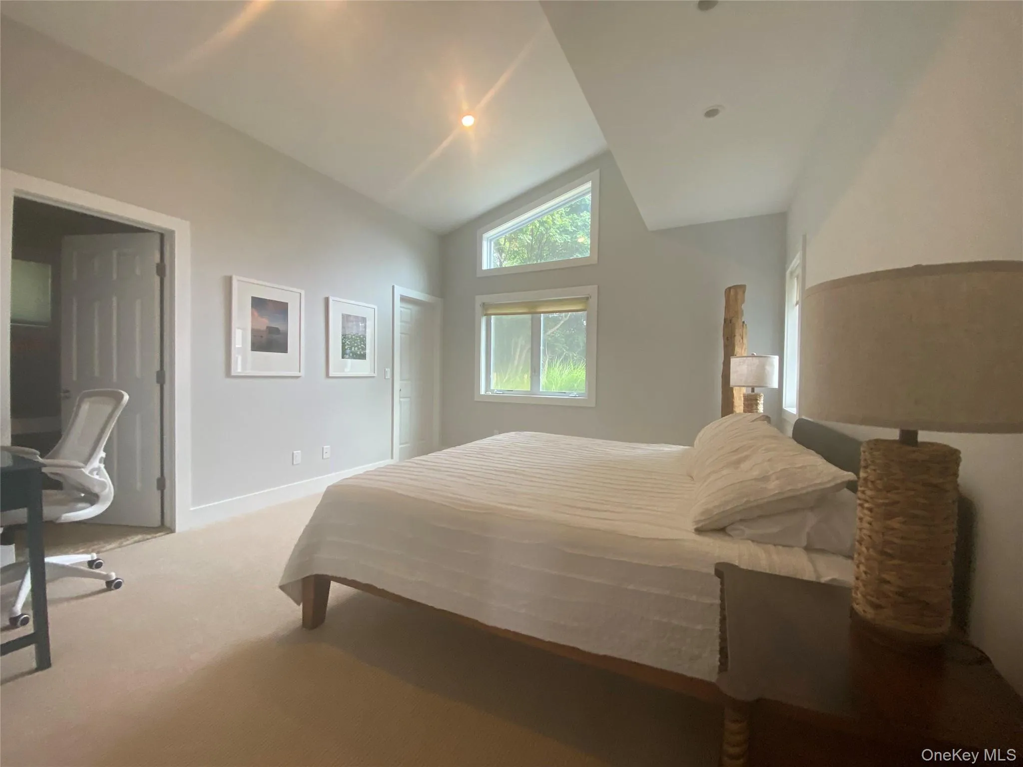 Carpeted bedroom featuring lofted ceiling and an office area Carpeted bedroom featuring lofted ceiling and an office area