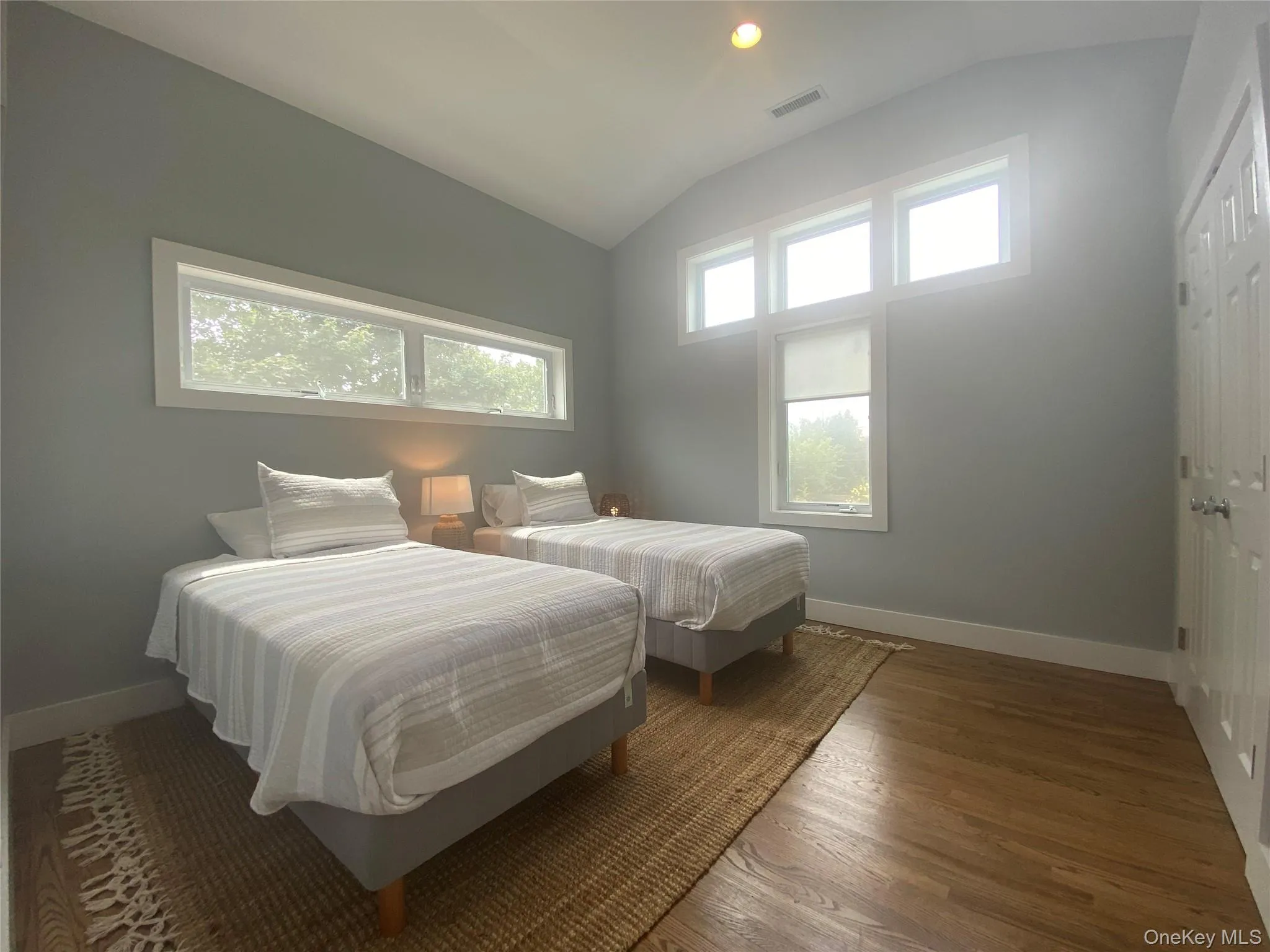 Bedroom with multiple windows, vaulted ceiling, wood finished floors, and a closet Bedroom with multiple windows, vaulted ceiling, wood finished floors, and a closet