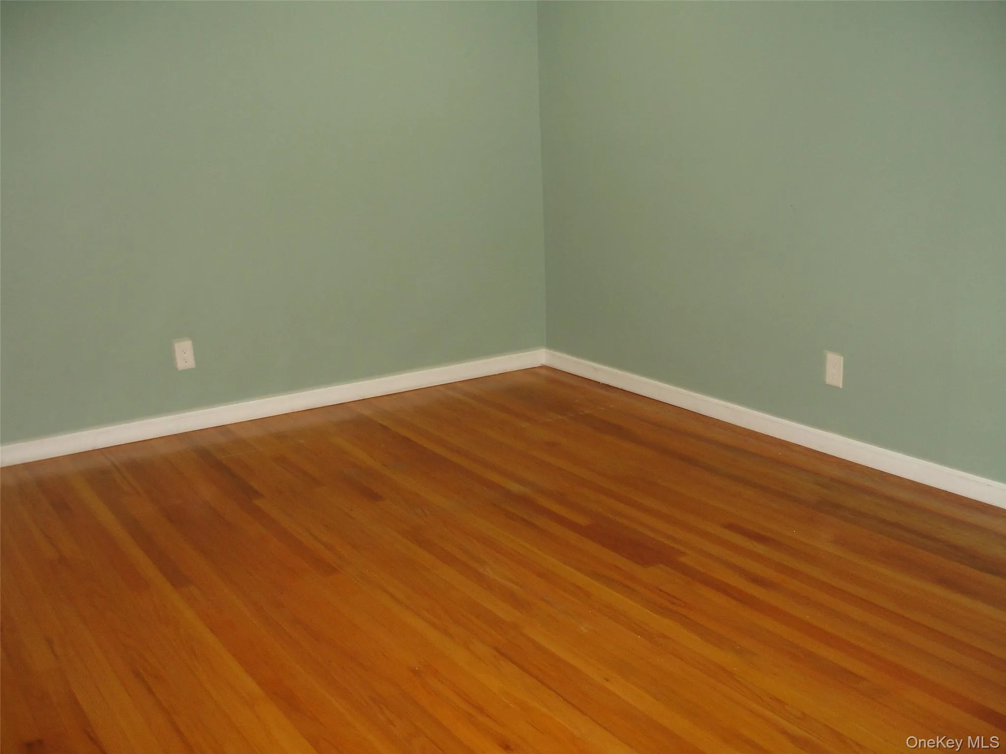 Unfurnished room with baseboards and wood finished floors Unfurnished room with baseboards and wood finished floors