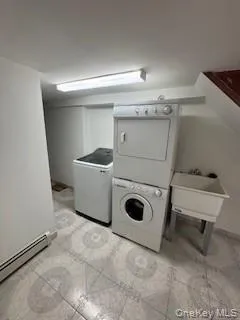Laundry area with stacked washer / dryer and a baseboard heating unit Laundry area with stacked washer / dryer and a baseboard heating unit