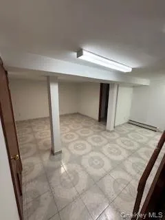 Finished below grade area with baseboard heating and light floors Finished below grade area with baseboard heating and light floors