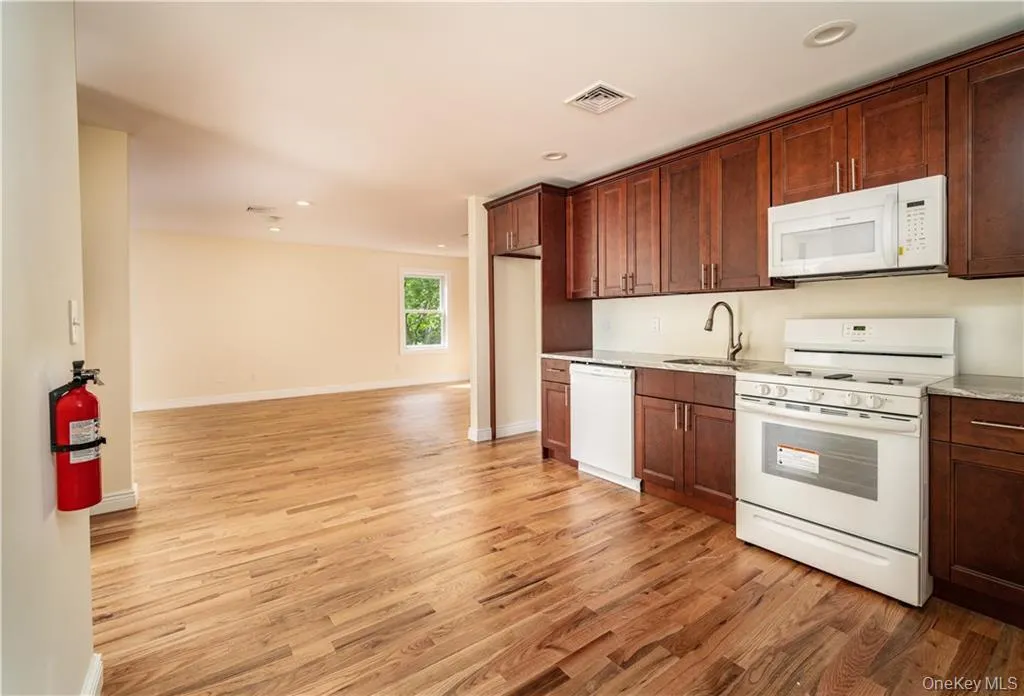 Kitchen featuring white appliances, light wood-style flooring, light countertops, recessed lighting, and open floor plan Kitchen featuring white appliances, light wood-style flooring, light countertops, recessed lighting, and open floor plan