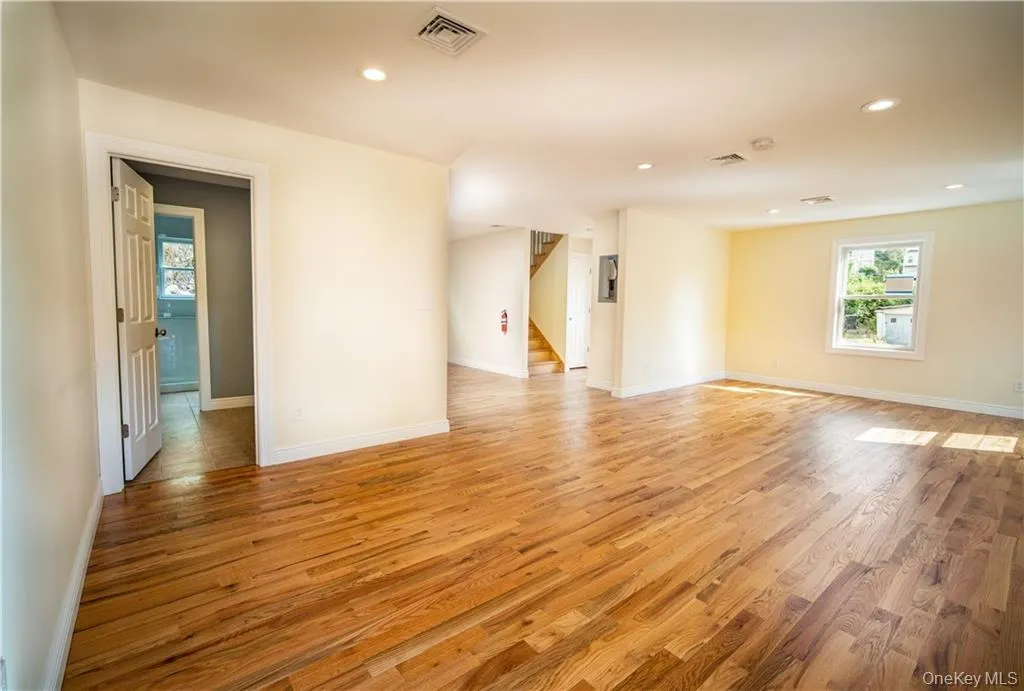 Unfurnished room with light wood-style floors, recessed lighting, and stairway Unfurnished room with light wood-style floors, recessed lighting, and stairway