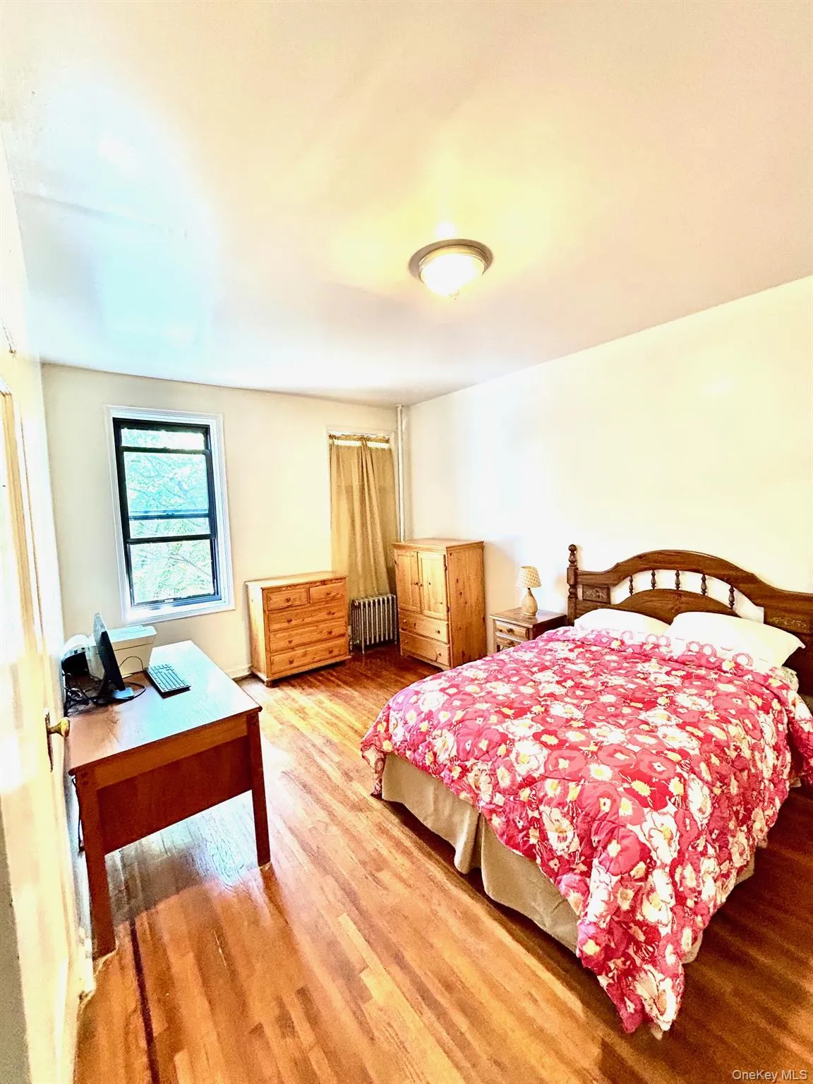 Master Bedroom featuring wood finished floors, radiator, and a desk Master Bedroom featuring wood finished floors, radiator, and a desk