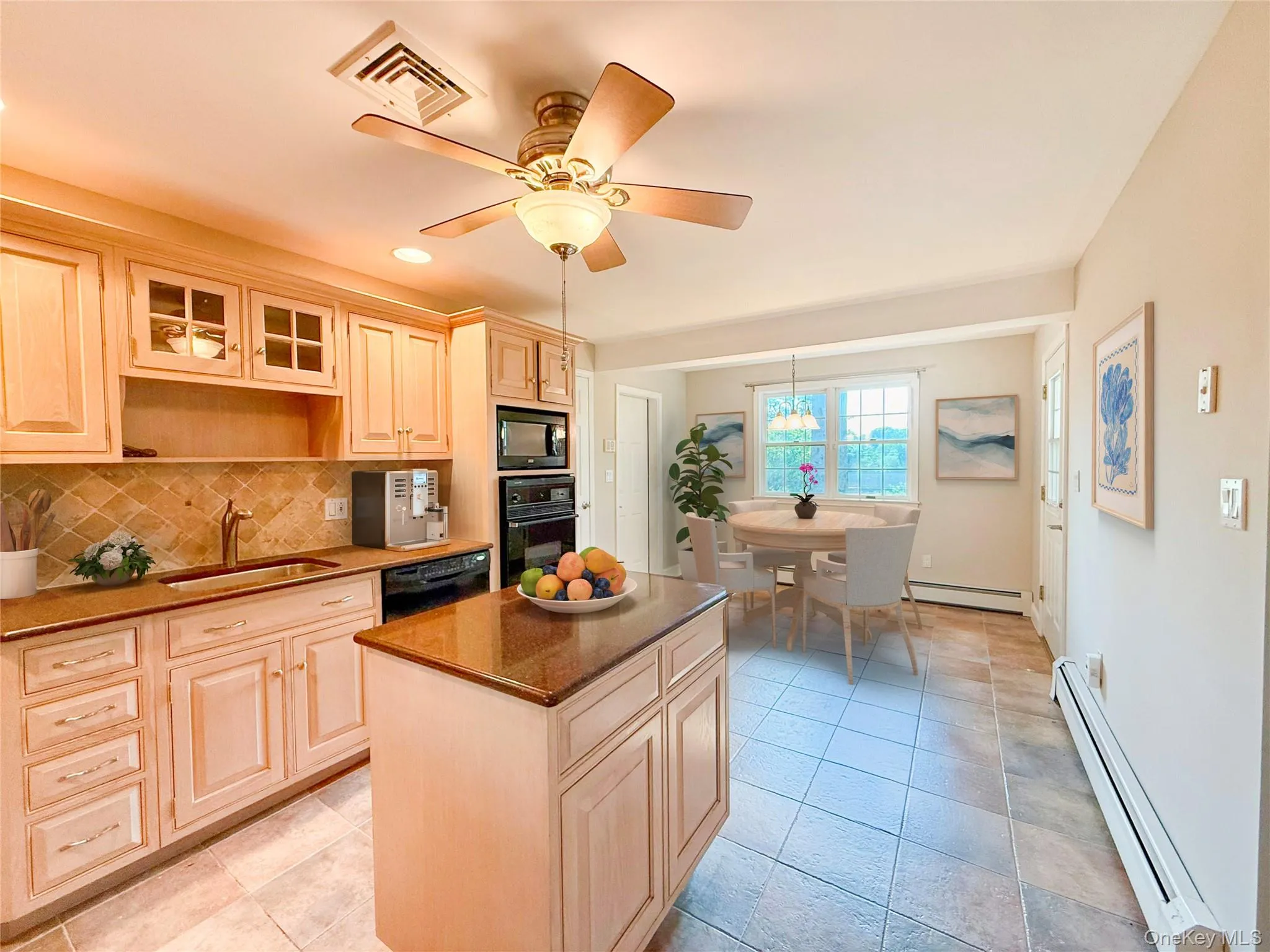 Kitchen with a baseboard heating unit, glass insert cabinets, decorative backsplash, black appliances, and a center island Kitchen with a baseboard heating unit, glass insert cabinets, decorative backsplash, black appliances, and a center island