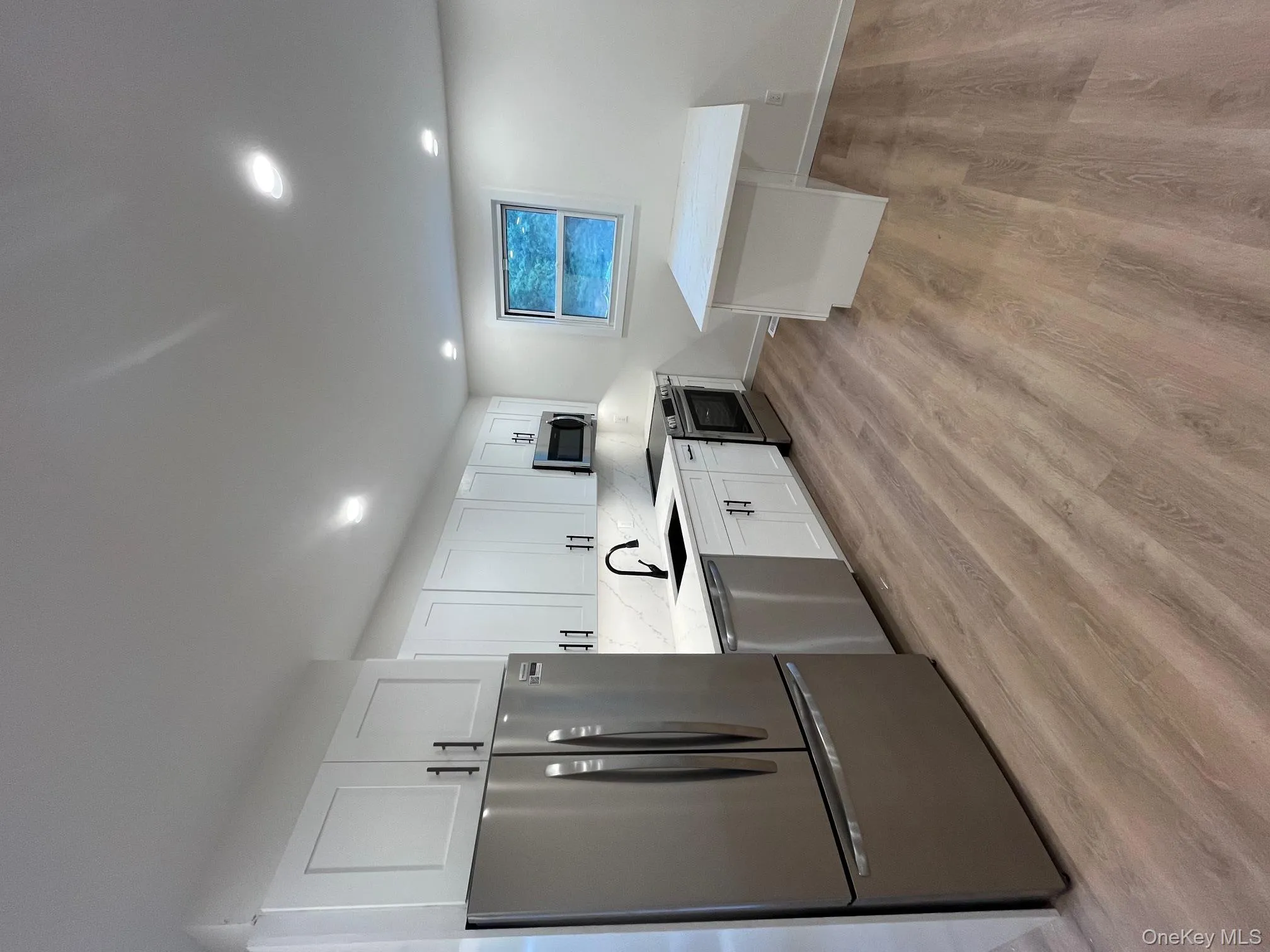 Kitchen featuring stainless steel appliances, white cabinets, light stone countertops, recessed lighting, and light wood finished floors Kitchen featuring stainless steel appliances, white cabinets, light stone countertops, recessed lighting, and light wood finished floors