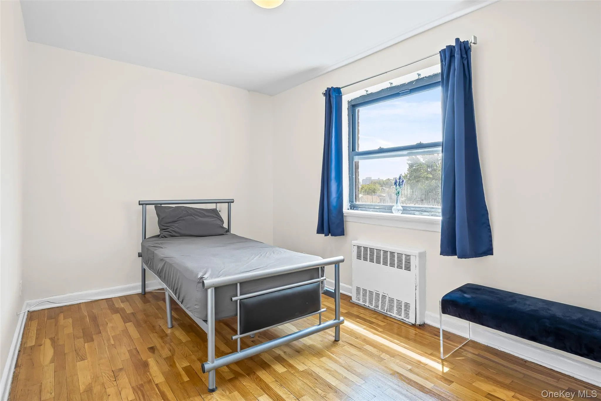 Bedroom featuring wood finished floors and radiator heating unit Bedroom featuring wood finished floors and radiator heating unit