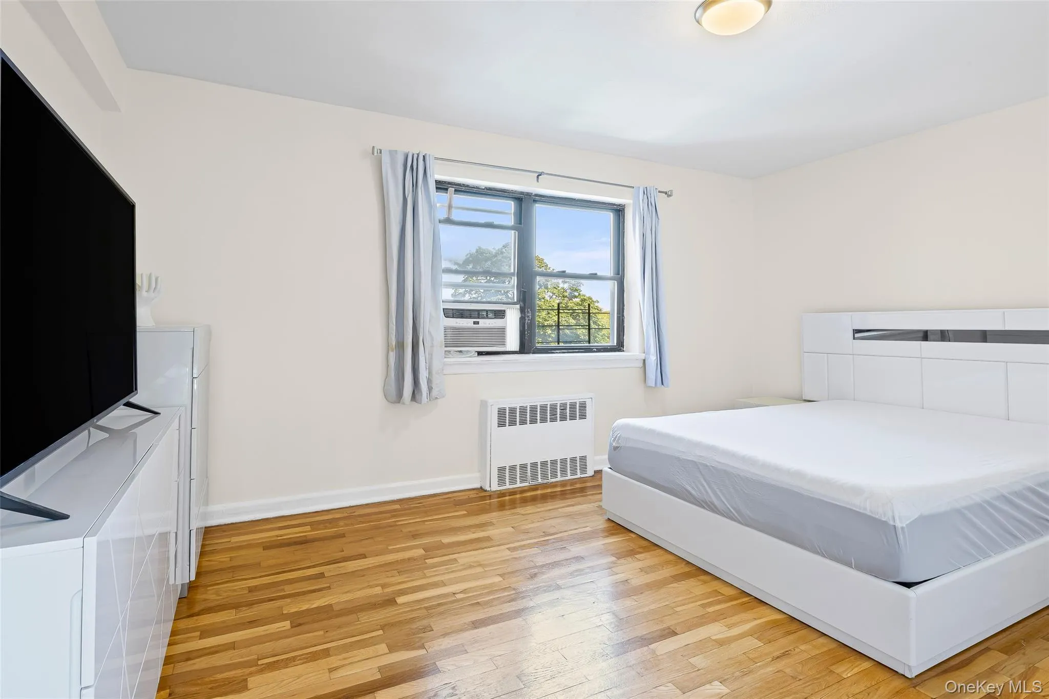 Bedroom featuring light wood finished floors and radiator Bedroom featuring light wood finished floors and radiator