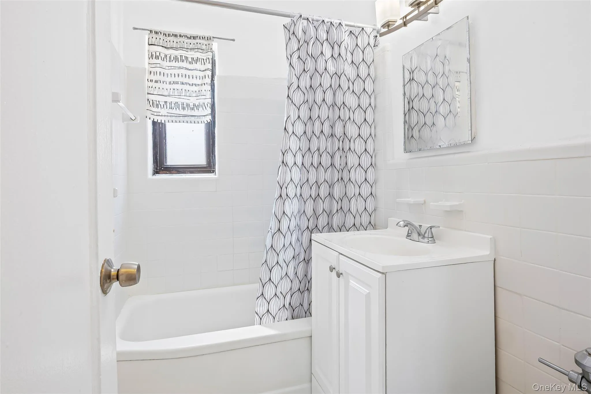 Bathroom featuring vanity, shower / tub combo, and tile walls Bathroom featuring vanity, shower / tub combo, and tile walls