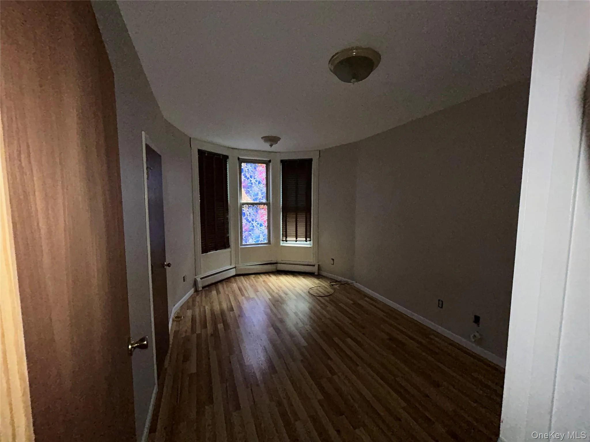 Spare room featuring dark wood-style flooring and baseboard heating Spare room featuring dark wood-style flooring and baseboard heating