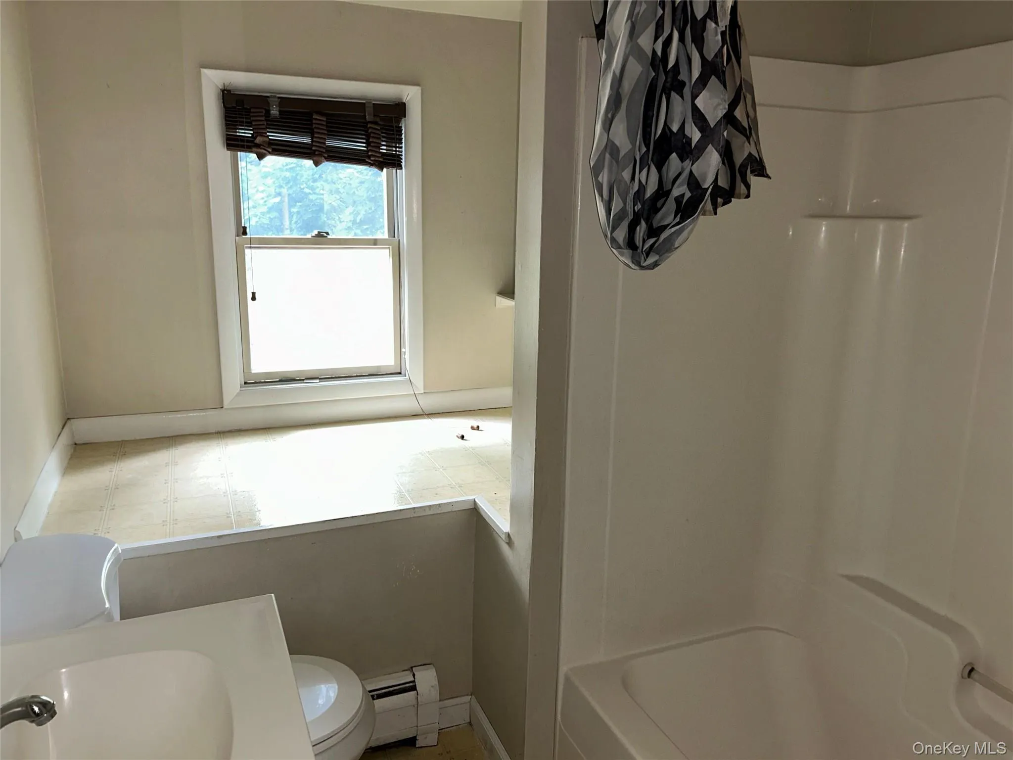Bathroom with a baseboard heating unit and shower / bath combination with curtain Bathroom with a baseboard heating unit and shower / bath combination with curtain