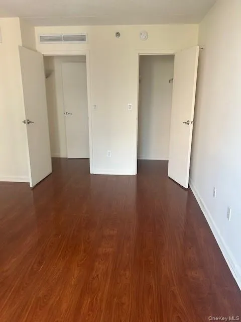 Empty room featuring dark wood finished floors and baseboards Empty room featuring dark wood finished floors and baseboards