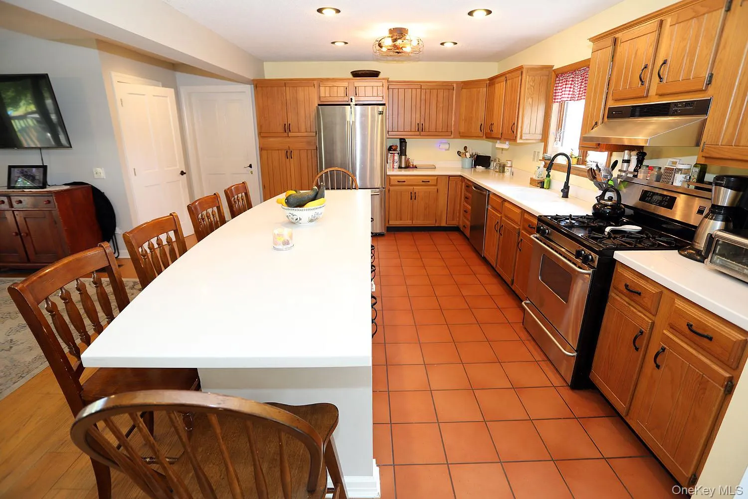 Kitchen with appliances with stainless steel finishes, under cabinet range hood, light countertops, and light tile patterned floors Kitchen with appliances with stainless steel finishes, under cabinet range hood, light countertops, and light tile patterned floors