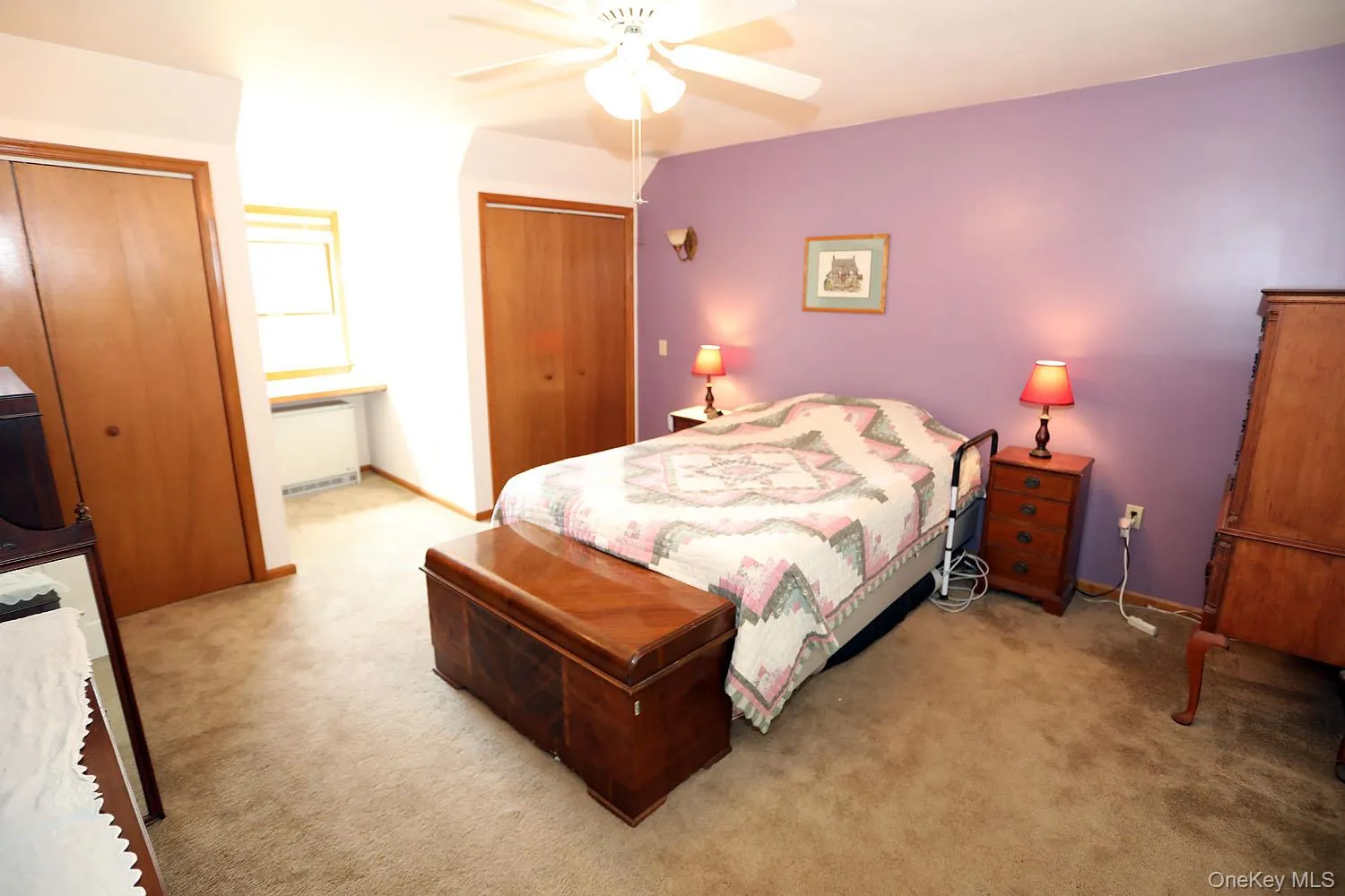 Carpeted bedroom featuring multiple closets, radiator heating unit, and ceiling fan Carpeted bedroom featuring multiple closets, radiator heating unit, and ceiling fan