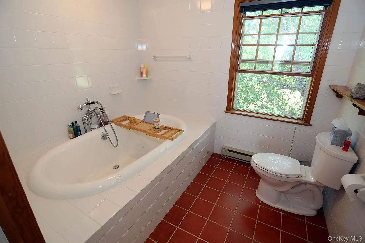 Bathroom featuring tile walls, tile patterned flooring, a bath, and a baseboard heating unit Bathroom featuring tile walls, tile patterned flooring, a bath, and a baseboard heating unit