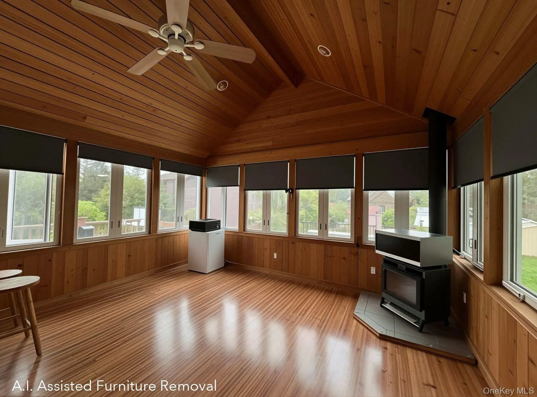 Insulated, wood-paneled three season room featuring a pellet stove, an angled vaulted ceiling with recessed lighting, a ceiling fan, and extensive wrap around windows with roller shades. Insulated, wood-paneled three season room featuring a pellet stove, an angled vaulted ceiling with recessed lighting, a ceiling fan, and extensive wrap around windows with roller shades.