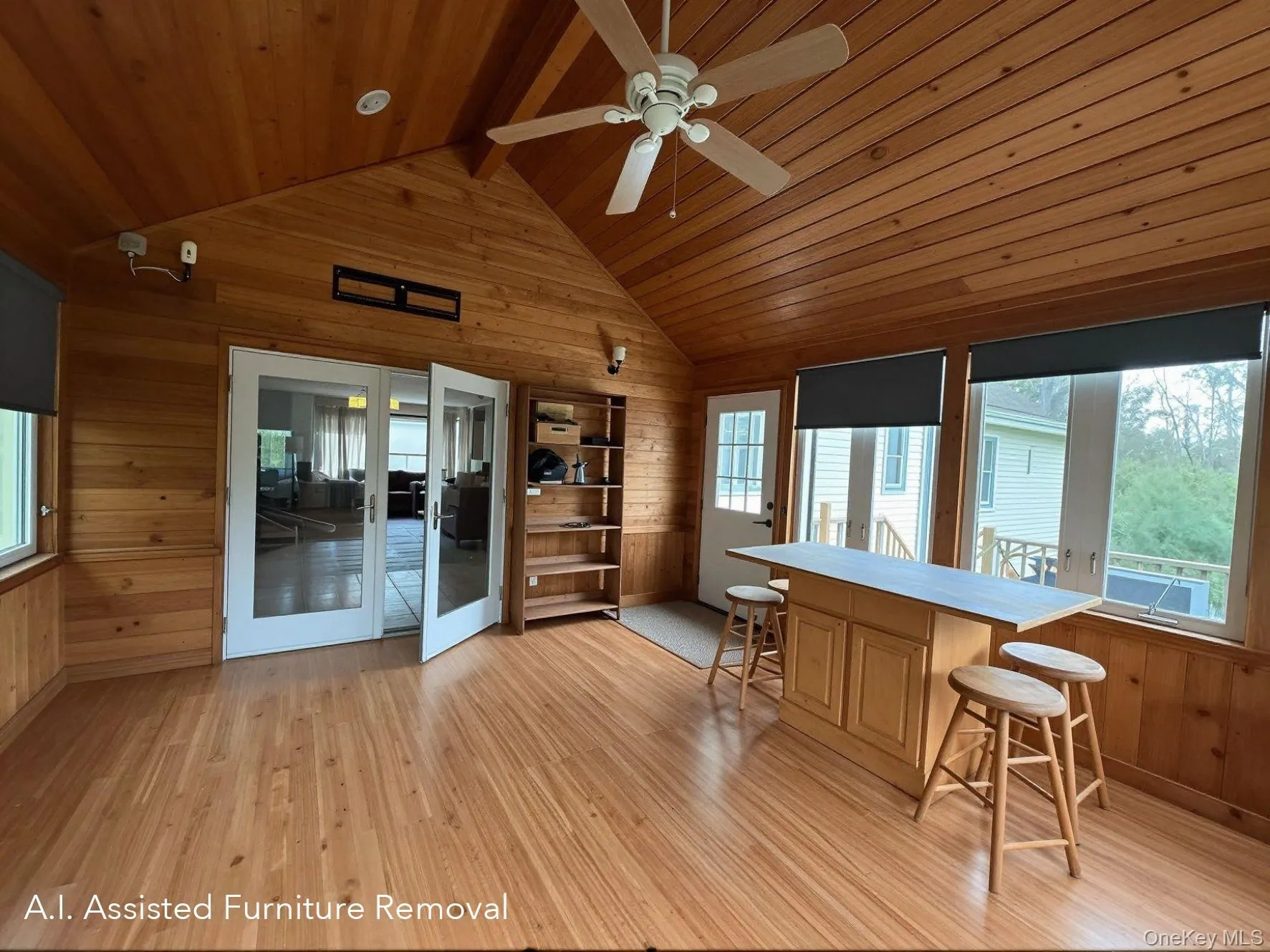 Insulated, wood-paneled three season room featuring a pellet stove, an angled vaulted ceiling with recessed lighting, a ceiling fan, and extensive wrap around windows with roller shades. Insulated, wood-paneled three season room featuring a pellet stove, an angled vaulted ceiling with recessed lighting, a ceiling fan, and extensive wrap around windows with roller shades.