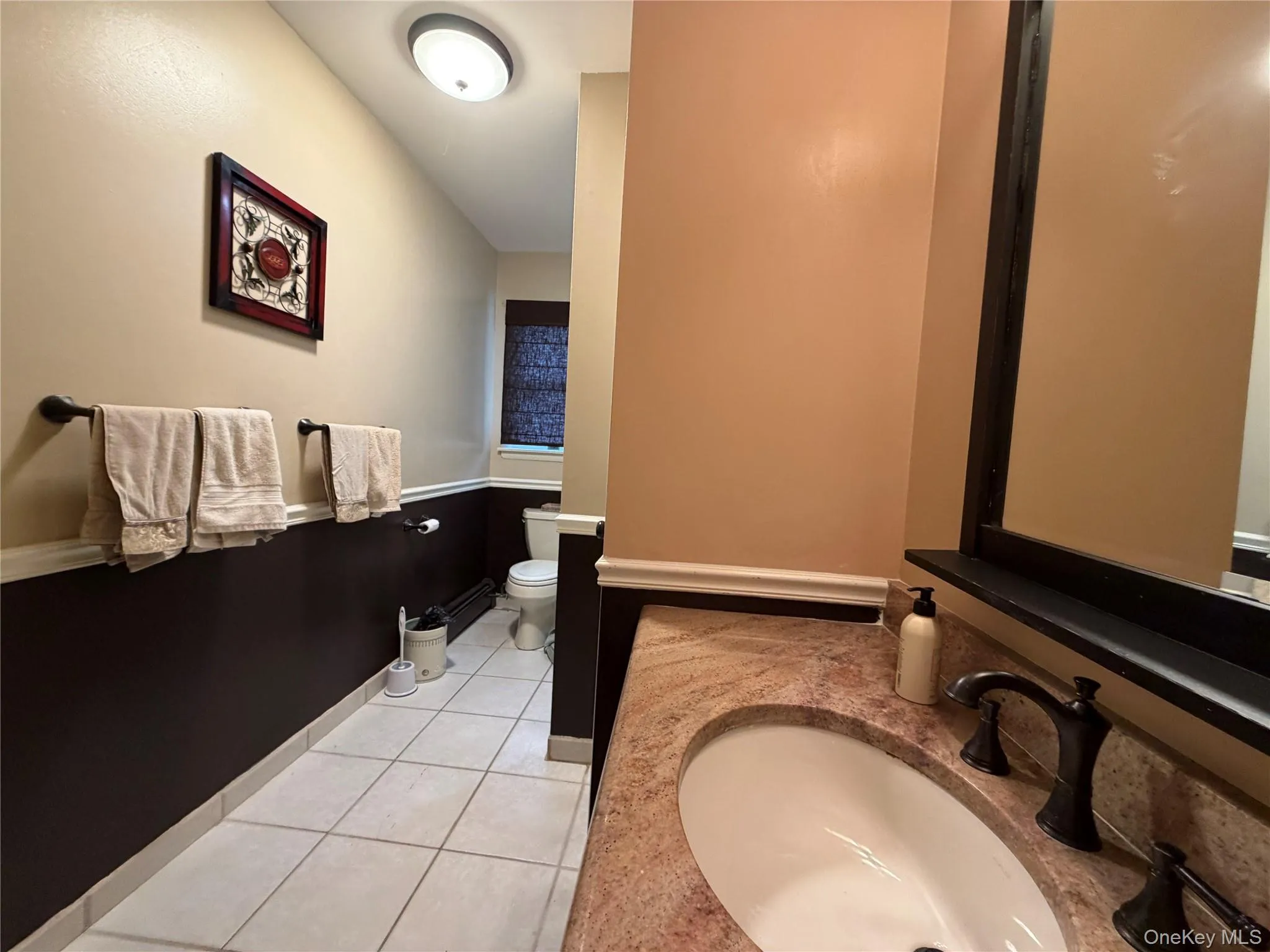 Hall bathroom featuring a vanity with a light-toned stone countertop and a dark-finished faucet Hall bathroom featuring a vanity with a light-toned stone countertop and a dark-finished faucet
