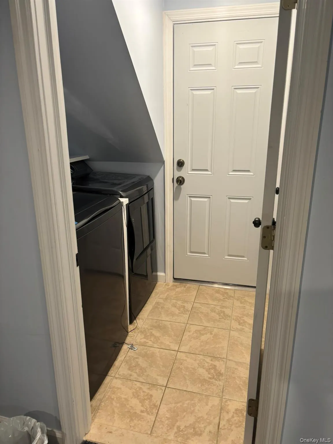 Washroom with washer and dryer and light tile patterned floors Washroom with washer and dryer and light tile patterned floors