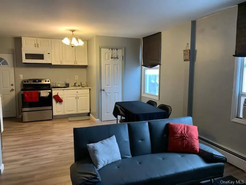 Kitchen featuring white cabinets, electric stove, light wood-style floors, white microwave, and a chandelier Kitchen featuring white cabinets, electric stove, light wood-style floors, white microwave, and a chandelier