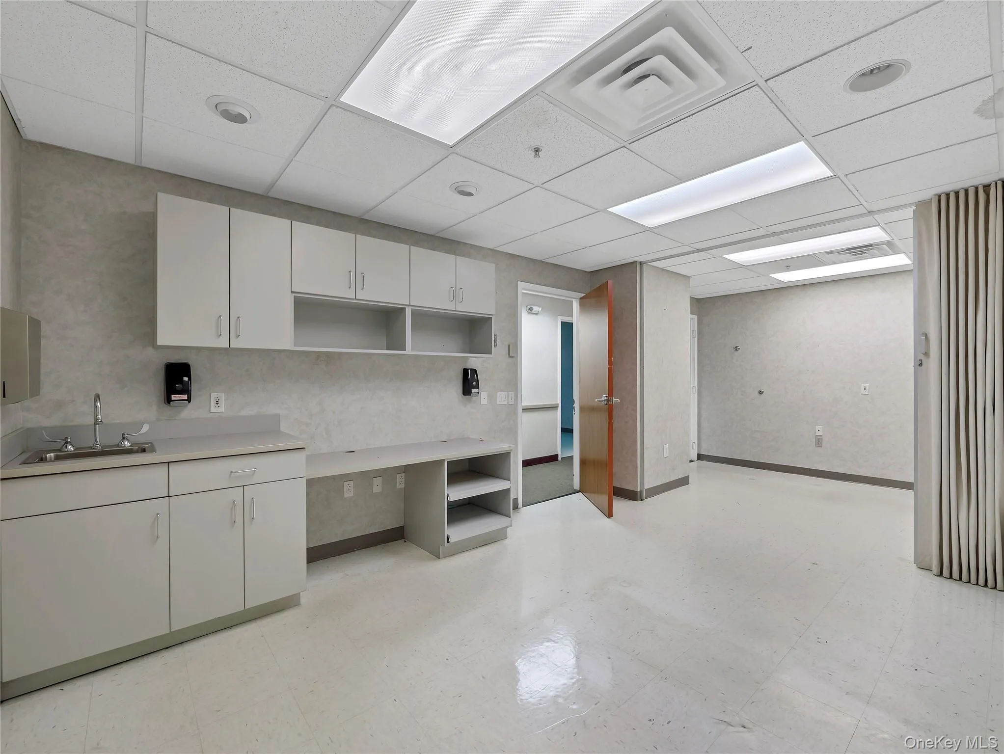 Kitchen featuring light floors, wallpapered walls, a paneled ceiling, light countertops, and open shelves Kitchen featuring light floors, wallpapered walls, a paneled ceiling, light countertops, and open shelves